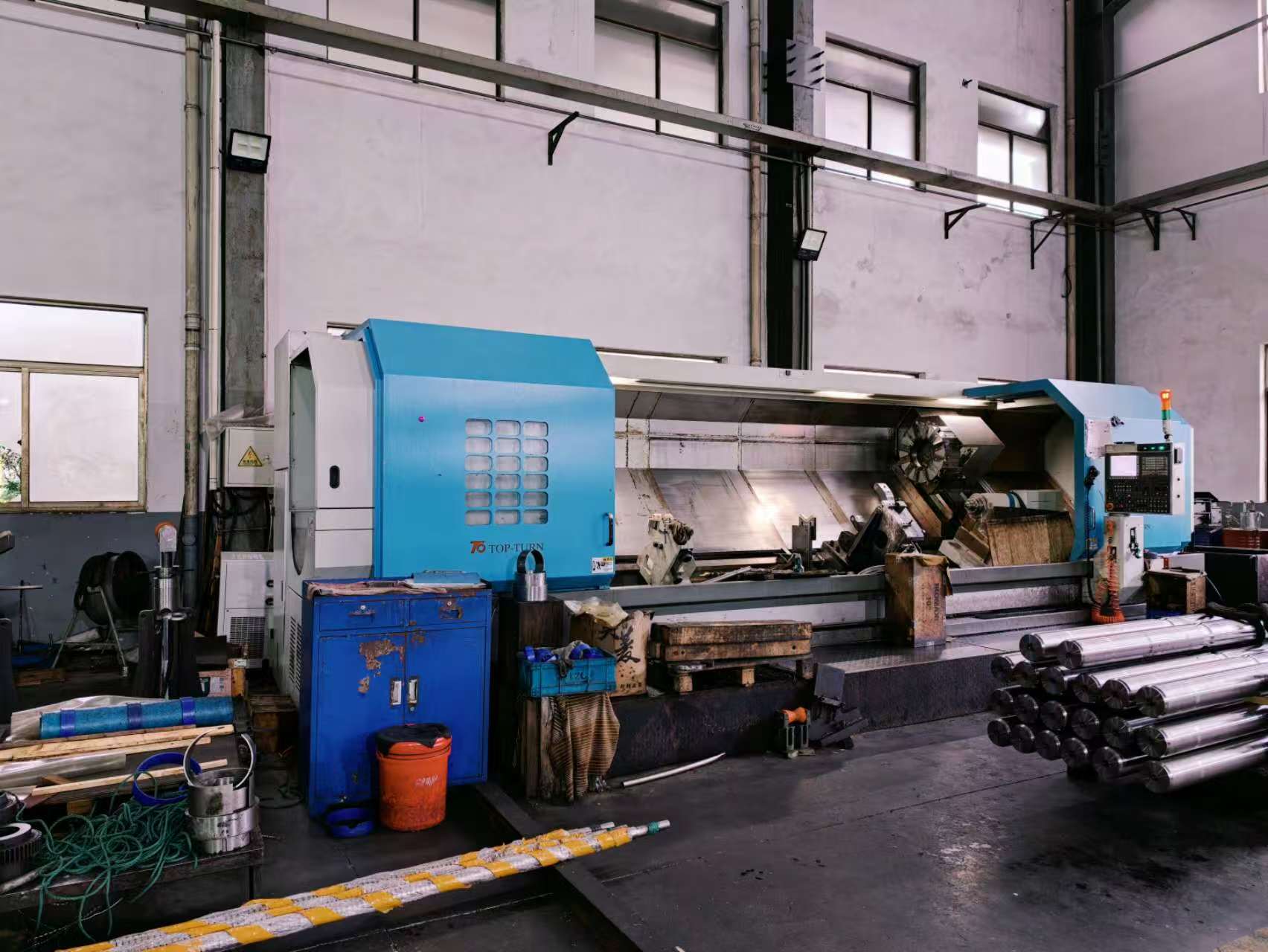 CNC lathe with steel shaft components in the foreground